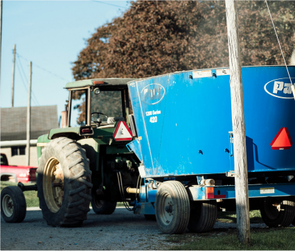 A tractor pulls a blue feed mixer.