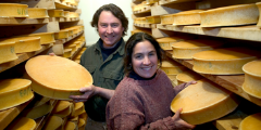 cheesemakers with wheels of cheese