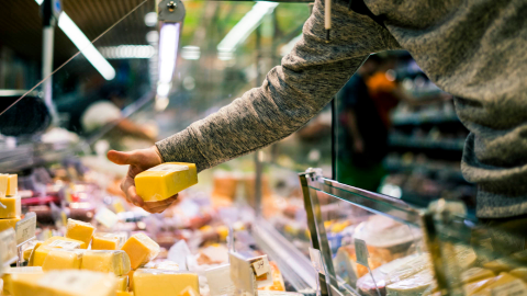 Close-up image of hand grabbing for cheese