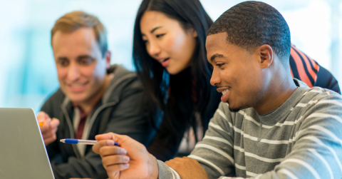 Three people are discussing something over a computer