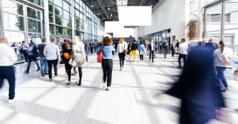 A busy crowd walks through a trade show