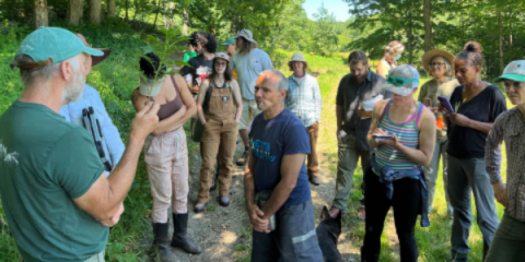  A group of individuals standing outside listening to someone speak