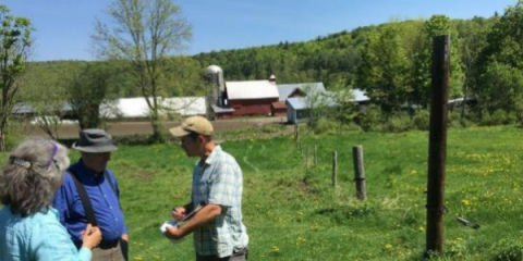 three people discussing something on a clipboard standing on a farm