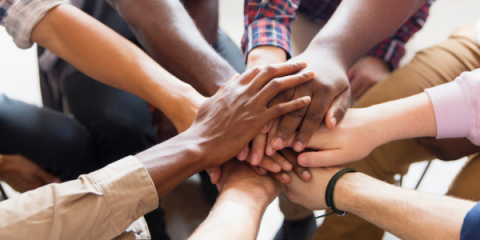 A group of people standing together with their hands touching in the middle