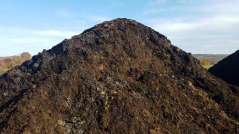 A brown compost pile against a blue sky