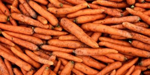 A close up photo of orange carrots without leaves that still have some soil on them.