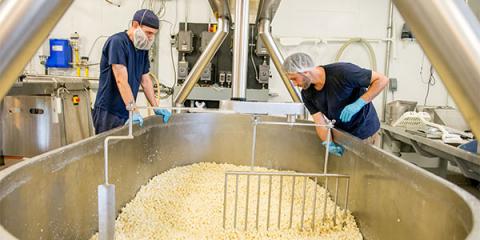 Two people mixing cheese curds